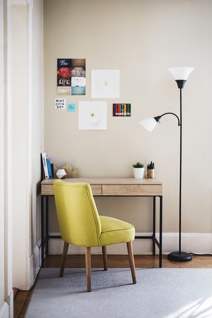 reading corner with fireplace glow, wood bookcase, brass lamp and green accents