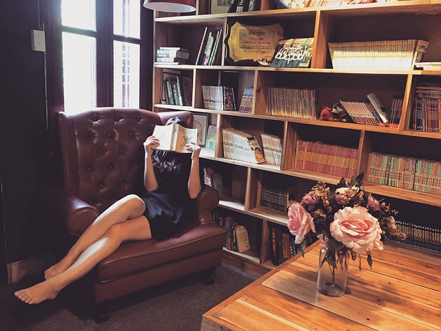 leather armchair in a reading room with wood shelves and brass floor lamp